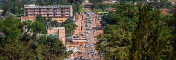 Rue animée de Kampala avec collines et ciel dégagé.