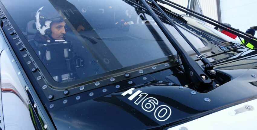 Cockpit H160 : pilote attentif, casque, tableau de bord.